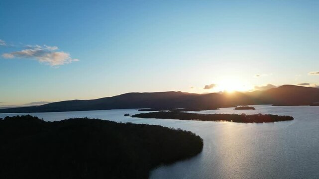 Aerial View of Calm Water of Massive Lake at Balmaha Valley Village Near Glasgow Landscape During Sunset. Village is a popular tourist destination for picnickers and day trippers from Glasgow