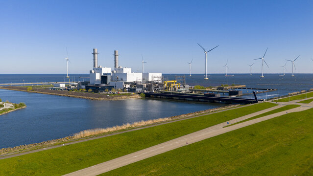 Lelystad, Netherlands - 21 April 2026: Aerial view of the Maxima plant power station and offshore wind turbines along the coast under a clear blue sky.