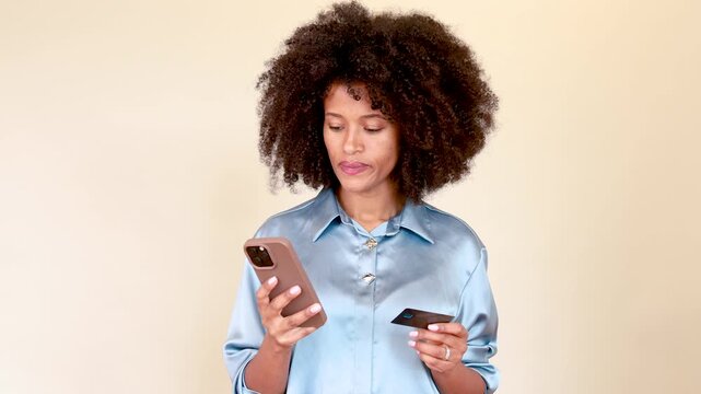 African american woman having issues with online shopping using smartphone and credit card, experiencing frustration and anger