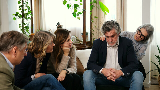 Family members supporting a sad senior man during a difficult time at home