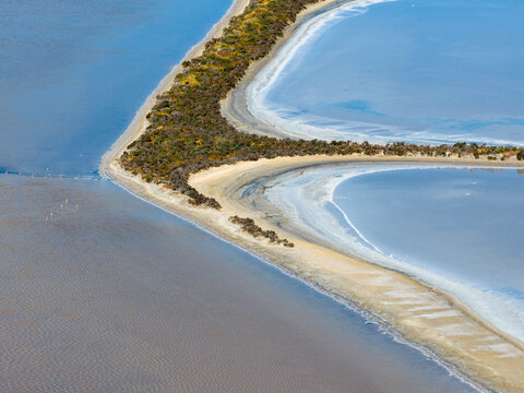 Aerial view of levee banks and crusty shorelines around manmade salt ponds