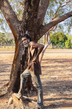 bearded aboriginal man in jeans and singlet standing under a tree in Derby