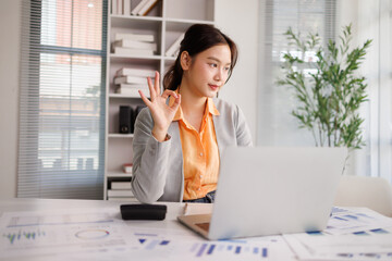 Obraz premium Asian businesswoman giving ok gesture during video call