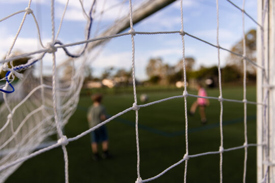 close up of soccer goal net with blurry kids playing in background