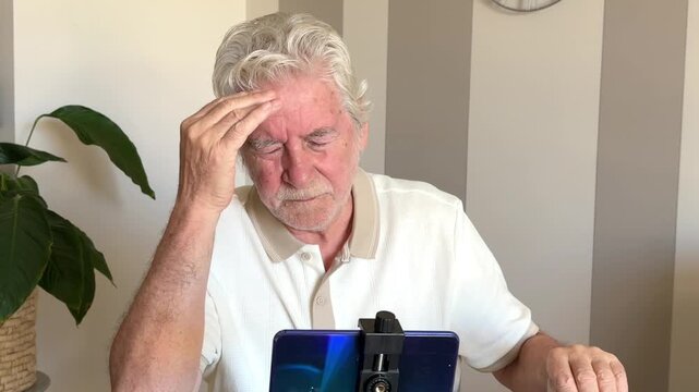 An elderly man experiences a painful headache and severe eye strain, rubbing his temples in discomfort after spending prolonged time looking at his smartphone. He appears tired and stressed.