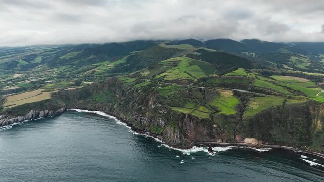 Dramatic volcanic coast with lush green hills rising above Atlantic Ocean on Sao Miguel Island, Azores