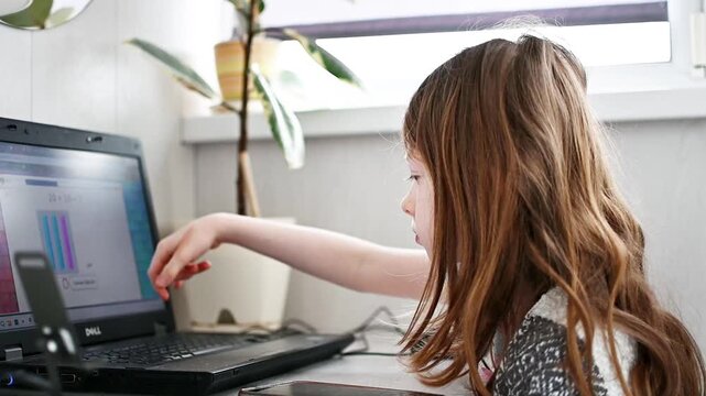 Smart caucasian middle School girl using laptop. Child typing on the keyboard. Online tutor teaching digital class, web lesson on computer at home. E-education. Schoolboy studying doing homework.