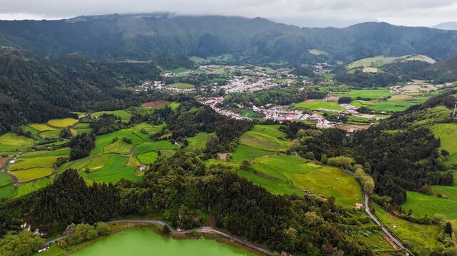 Green agricultural landscape near Lagoa das Furnas on Sao Miguel island, Azores. Rural fields, forested hills and village area. Aerial view