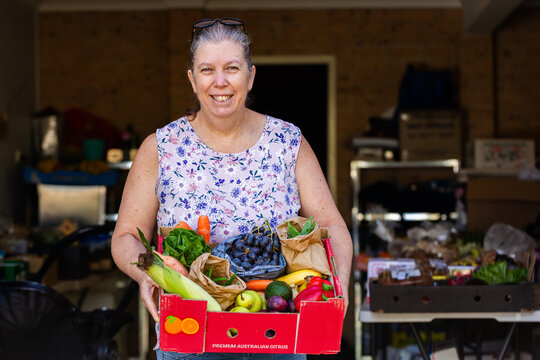 Box of fresh organic fruit and veggies from local Box Divvy hub held by woman