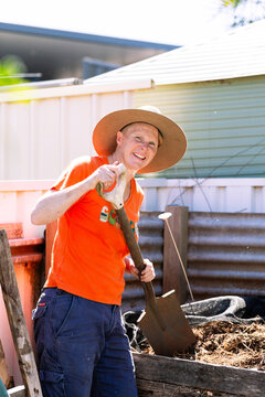 Australian woman in backyard garden ready to turn soil in compost container