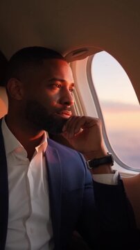 Successful businessman looking through private jet window