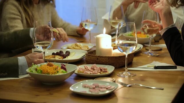Friends socializing and eating together at a candlelight dinner party with wine and appetizers