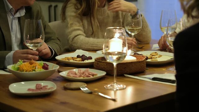 Group of people enjoying appetizers and white wine at a cozy restaurant with candlelit ambiance