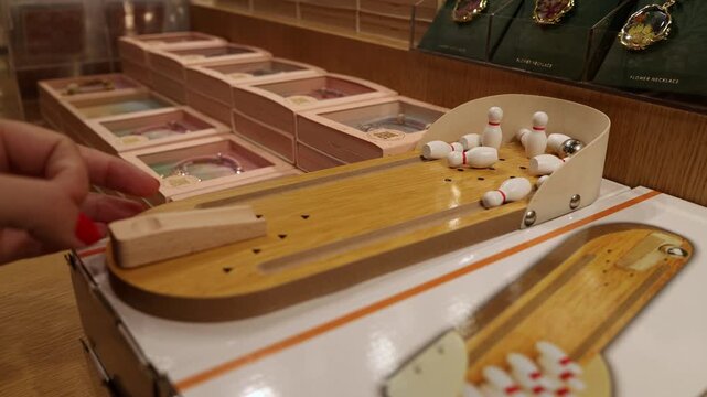 Mini tabletop bowling game with wooden lane and tiny pins in cozy indoor shop setting Guangzhou China close up playful leisure concept