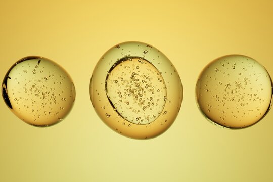 Golden oil droplets with bubbles on yellow background