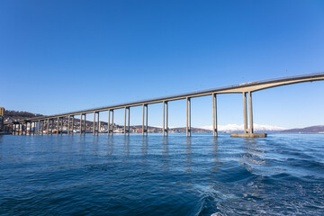 Obraz premium Tromsø Bridge seen from moving boat over Arctic fjord in Northern Norway