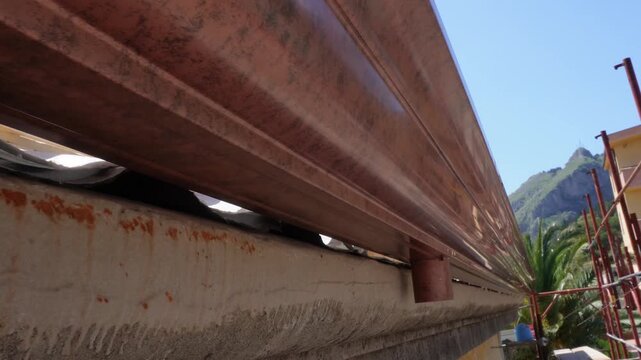Installation of a gutter system. Drainage system for rainwater. Close-up of a professional installation of a brown metal gutter on the roof of a building.