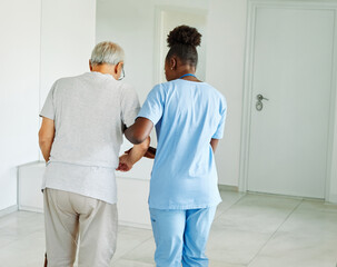Fototapeta premium Doctor or nurse caregiver helping senior man holding walking cane at home or nursing home