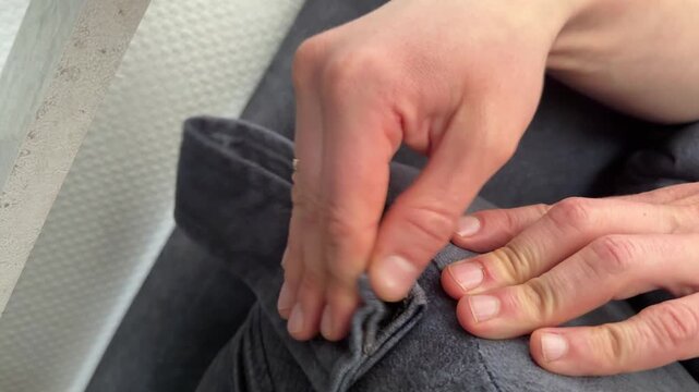 Hands opening and closing a Velcro fastener on a sofa cushion cover. Close up of separating and attaching hook and loop tape on furniture upholstery. Everyday home furniture maintenance concept