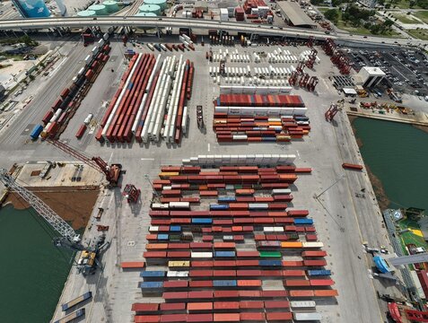 Riviera Beach, United States - 15 April 2026: Aerial view of the Port of Palm Beach container terminal with rows of colorful shipping containers, industrial cranes, and a highway overpass.