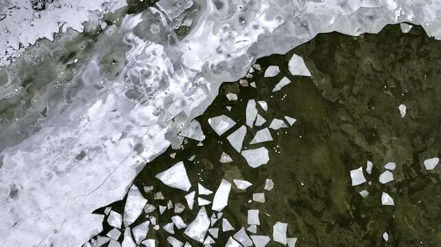 Aerial still top down video of frozen Baltic Sea coastline at T&uuml;risalu, Estonia, broken ice floes, cracked white surface and dark water contrast. Cold winter day, snow covered textures.