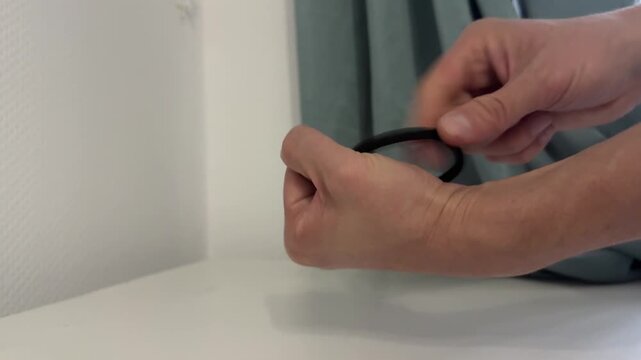 Hand pulls and releases a black hair tie in a quick motion