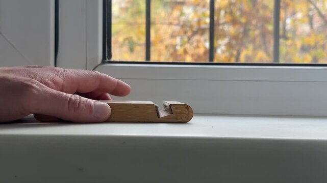 Tapping a wooden phone holder rhythmically on a windowsill
