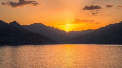 Fototapeta premium Golden sun dips behind rugged mountains
