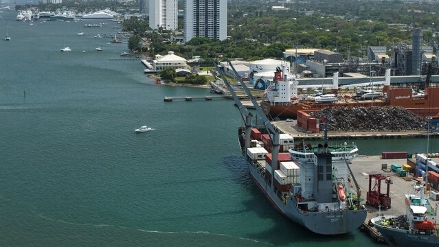 Riviera Beach, United States - 15 April 2026: Aerial view of large cargo ships docked at the port with industrial facilities and high-rise buildings along the waterfront.