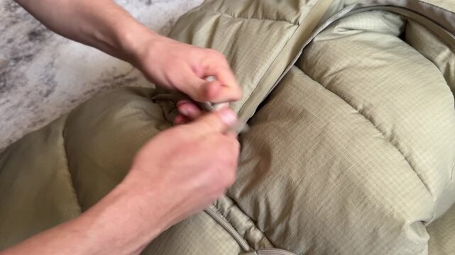 Hands tightening and loosening a drawstring on a padded winter jacket hood. Close up of adjusting clothing cord on outerwear. Everyday clothing adjustment and winter apparel detail concept