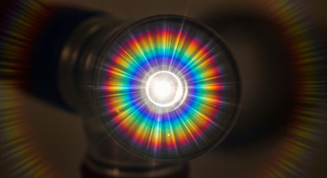 Bright light shining through a glass lens with rainbow diffraction