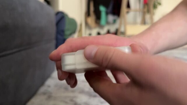 A person opens a round plastic lip balm container with both hands