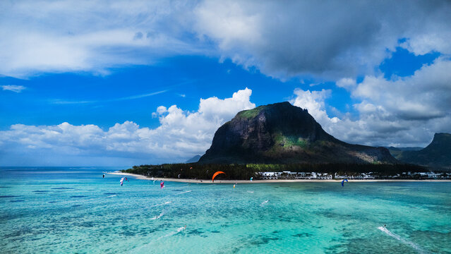 Kitesurfers glide across the crystal turquoise lagoon of Le Morne beach, Mauritius, with the iconic UNESCO-listed Le Morne Brabant mountain rising dramatically behind.