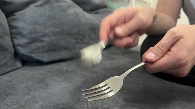Hand tapping a fork against a fork