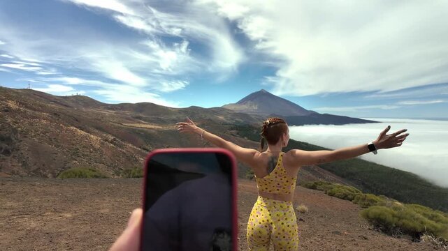 Person filming woman posing at mount teide volcano