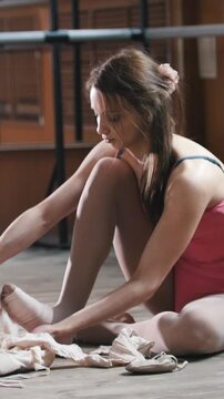 Girl balerina dancer putting on her ballet shoes