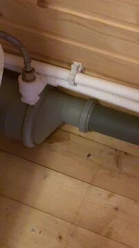 Inspecting a plumbing pipe in a wooden room during the day