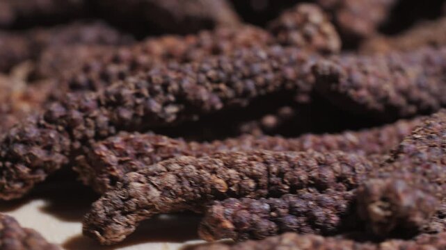 Indonesian long black peppercorns, close up of spices, dry hot pepper. 