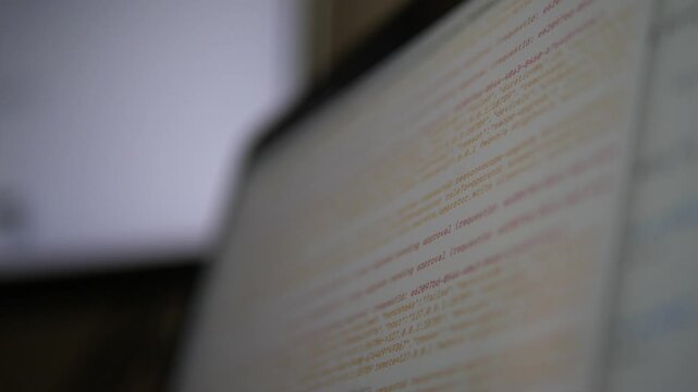 Cinematic out-of-focus diagonal background of a computer monitor displaying technical logs and software code, abstract high-tech and cyber security concept with copy space