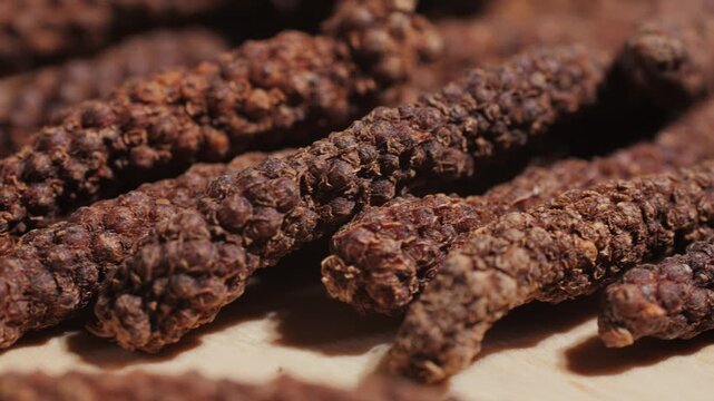 Indonesian long black peppercorns, close up of spices, dry hot pepper. 