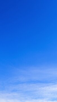 Beautiful blue sky with almost no clouds. White altocumulus cloudscape appear and cover the sky. Low angle view. Vertical video