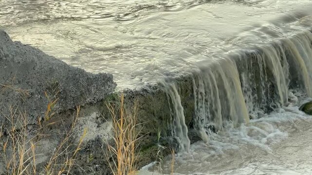 Waterfall flowing over concrete dam wall