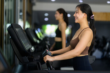 Fototapeta premium Young smiling asian woman exercising on treadmill in gym