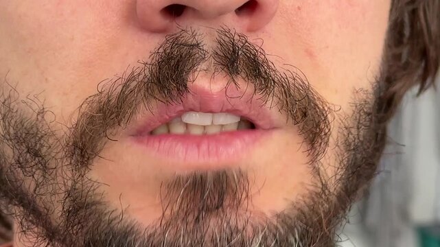 Close-up of a man chattering his teeth. Subtle jaw movement with beard and mustache visible