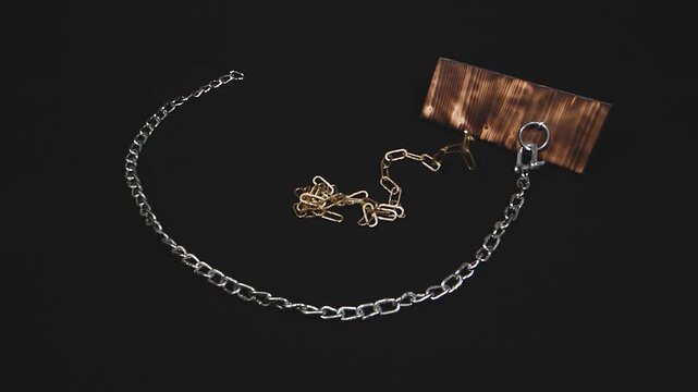 Slow-motion footage of metal chains falling from above onto a black background.