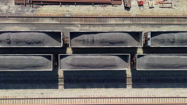 Industrial freight train hopper cars loaded with coal, top down aerial video.