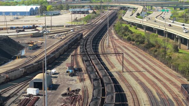 Aerial video of a large-scale industrial coal export terminal featuring loaded hopper cars on parallel rail tracks and heavy processing infrastructure.