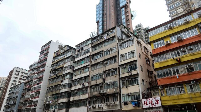 Sham Shui Po, Kowloon, Hong Kong- 8 Feb 2026: old tenement apartment building with shops on the ground floor and a high rise residential blocks at the back in day time