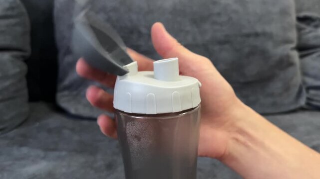 Close-up of hand opening and closing a shaker bottle lid.