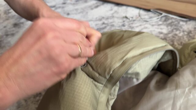 A person pulls on the drawcord of a jacket hood to adjust the fit around their head